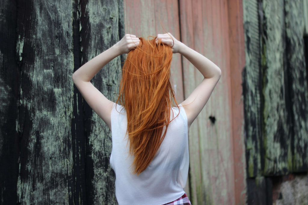 woman with red hair hands on head 